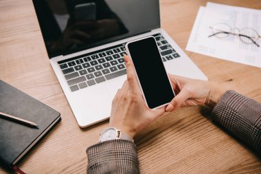 dizüstü bilgisayar ve belgeleri işyerinde smartphone kullanarak işkadını görünümünü kırpılmış