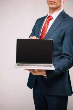 cropped view of businessman in suit presenting laptop isolated on grey clipart