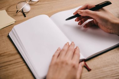Kadın defter gözlüklü işyerinde yazma görünümünü kırpılmış