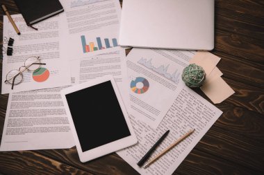 ahşap masa üzerinde dijital tablet ve işle ilgili belgeleri üstten görünüm