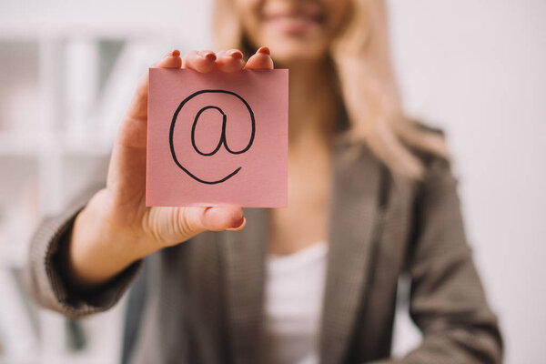 selective focus of businesswoman holding paper note with email sign 