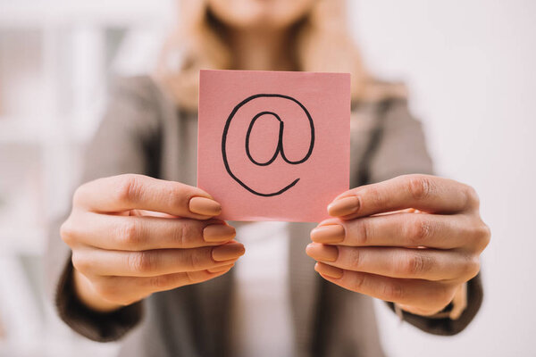 cropped view of businesswoman holding paper note with email sign 