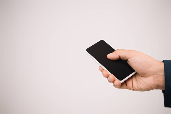 cropped view of businessman using smartphone isolated on grey