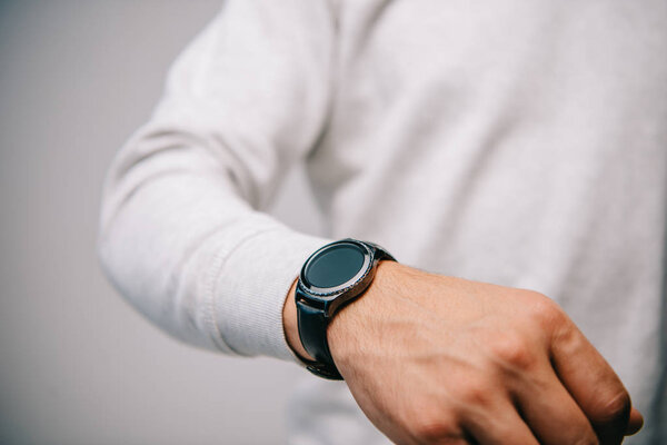 partial view of man with wristwatch on hand isolated on grey