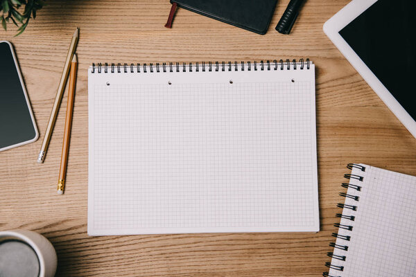 top view of business supplies, digital devices and empty notebook on workplace