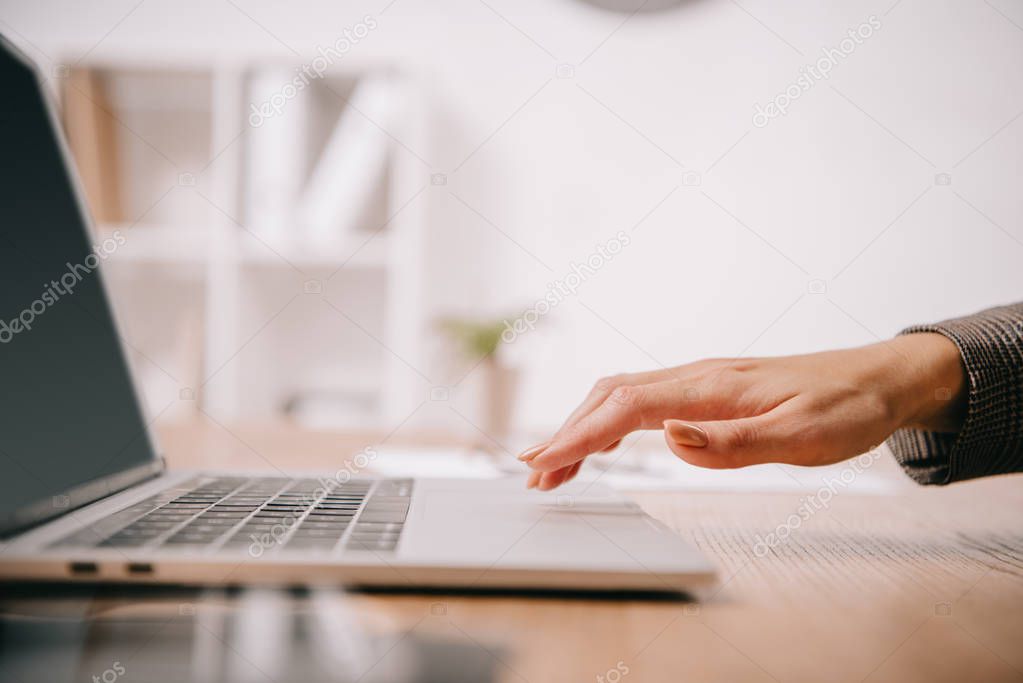 cropped view of businesswoman typing on laptop at workplace 