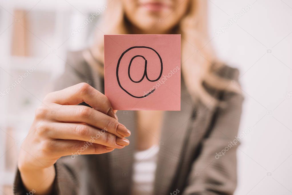partial view of businesswoman holding paper note with email symbol 