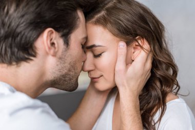 close up of happy man kissing nose of girlfriend  clipart