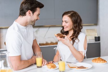 çekici kadın erkek yakınındaki çikolata ile tost ekmeği tutarken gülümseyen