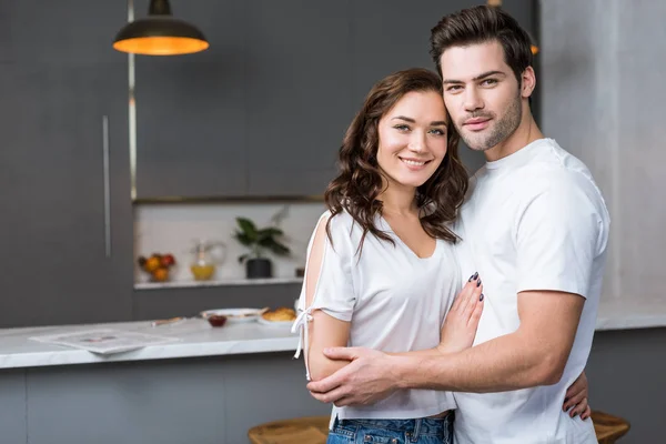 Glückliches Paar Blickt Die Kamera Und Umarmt Sich Der Küche — Stockfoto
