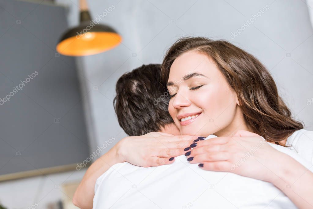 happy attractive woman hugging boyfriend and smiling at home