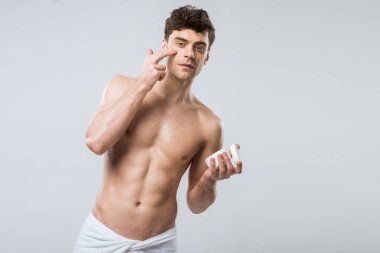 gömleksiz yakışıklı yüzündeki gri izole kozmetik krem uygulamak