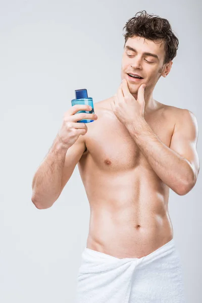 Hombre Guapo Mirando Botella Con Colonia Aislado Gris — Foto de Stock