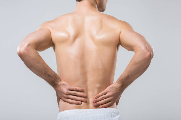 rear view of man having back pain, isolated on grey 