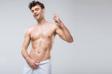 neşeli yakışıklı adam gri izole parfümler, püskürtme 