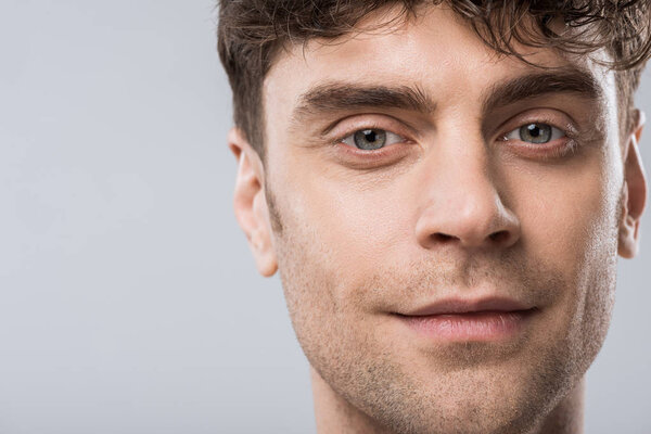 портрет красивого молодого улыбающегося человека, изолированного на сером
