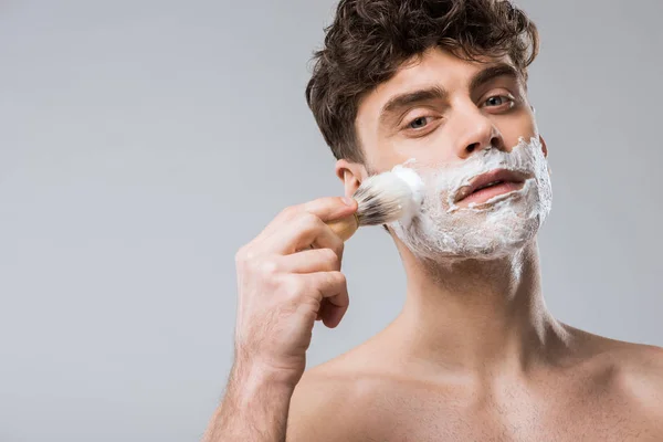 Jovem Bonito Aplicando Espuma Barbear Com Escova Isolado Cinza — Fotografia de Stock