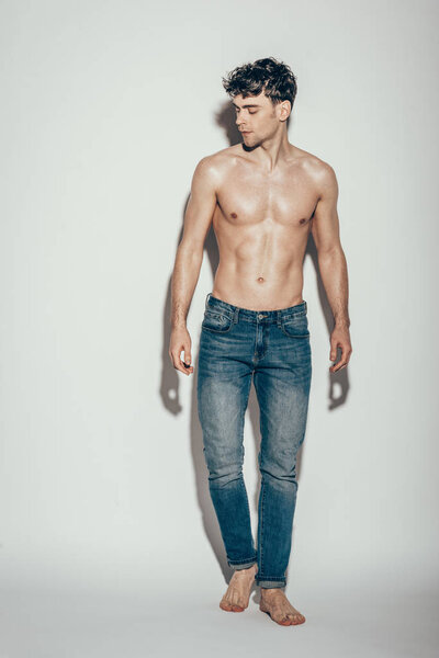 sexy shirtless muscular macho in jeans posing on grey