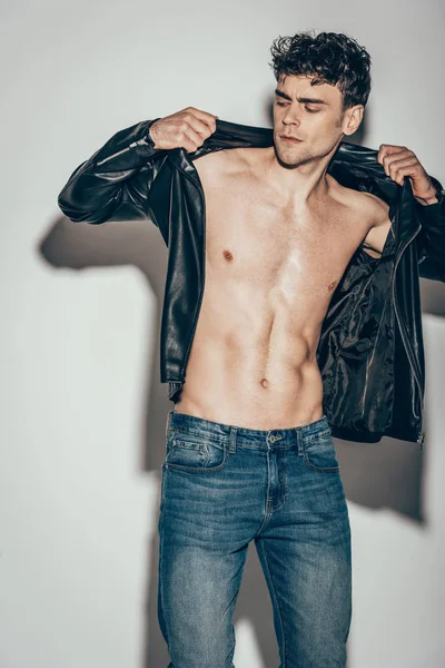 Sexy Mann Posiert Jeans Und Trägt Schwarze Lederjacke Auf Grau — Stockfoto