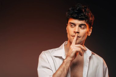 Sus işareti, izole kahverengi üzerinde gösterilen beyaz tişörtlü şık adam