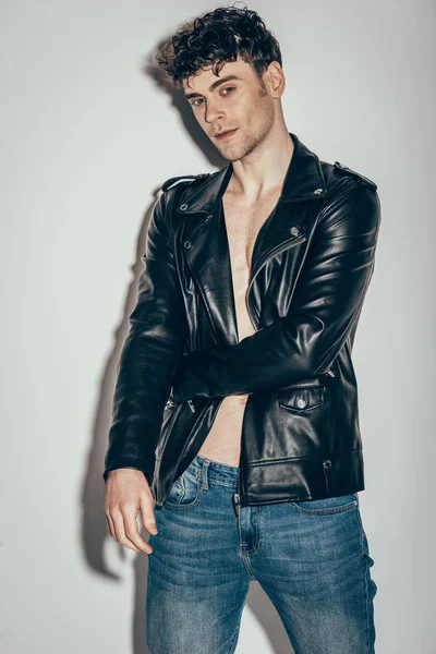 Stylischer Sexy Mann Posiert Jeans Und Schwarzer Lederjacke Auf Grau — Stockfoto