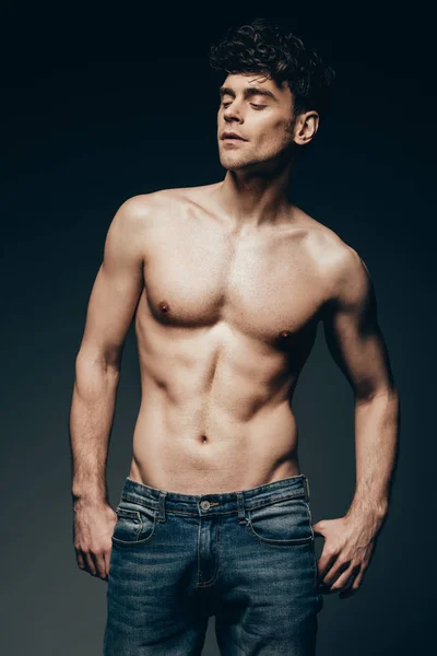 sexy shirtless muscular man in jeans posing isolated on dark grey