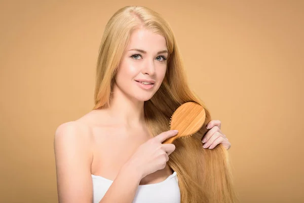 Heureuse Femme Blonde Brossant Les Cheveux Longs Sur Fond Doré — Photo
