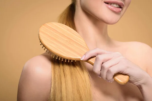 裁剪拍摄的裸体金发女孩刷头发与木毛刷孤立在米色 — 图库照片