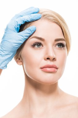 cropped shot of cosmetologist in latex glove touching forehead of beautiful woman isolated on white  clipart