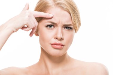 unhappy young woman pointing at wrinkles on forehead and looking at camera isolated on white   clipart