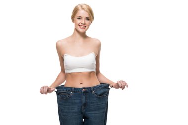 beautiful happy slim girl in oversized jeans smiling at camera isolated on white 
