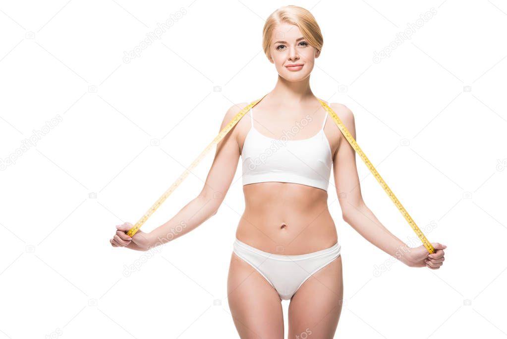 beautiful slim girl in underwear holding measuring tape around neck and smiling at camera isolated on white