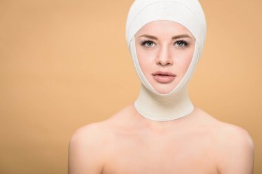 bej üzerinde izole kamera üzerinde kafa bakarak bandaj ile çıplak kadın