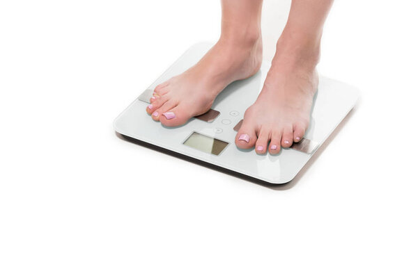 cropped shot of female feet standing on scales isolated on white