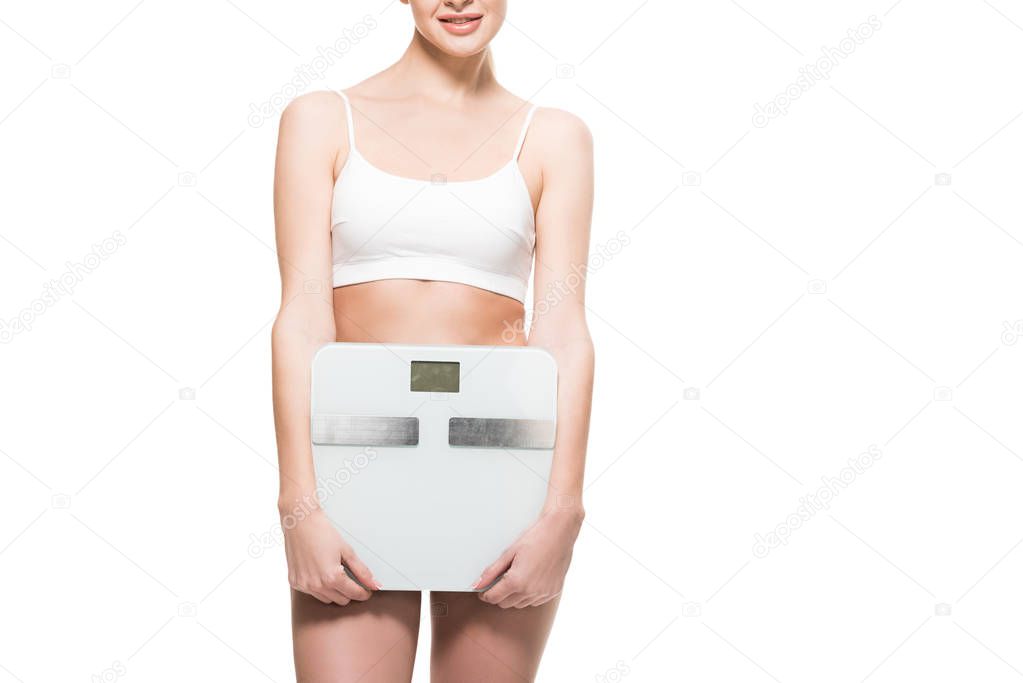 cropped shot of smiling young woman in underwear holding scales isolated on white