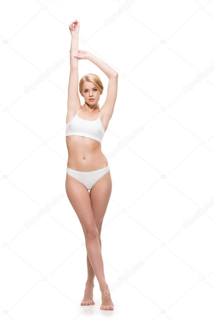 full length view of beautiful slim girl in underwear raising hands and looking at camera isolated on white