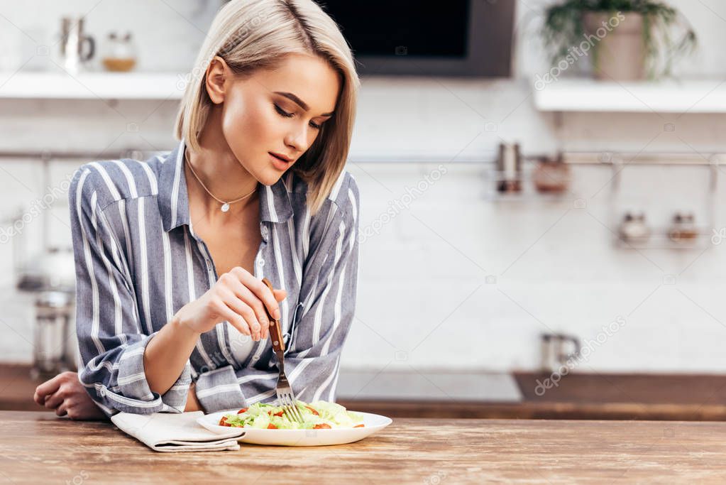 selective focus of attractive woman eating salad