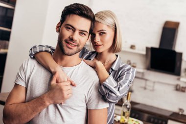 seçici odak sarılma ve kameraya gülümseyen çekici kız ve yakışıklı erkek