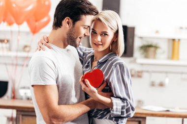 selective focus of handsome boyfriend giving gift to attractive girlfriend on Valentine's day