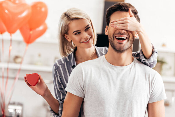 selective focus of attractive girlfriend hugging and giving gift to handsome boyfriend on Valentines day