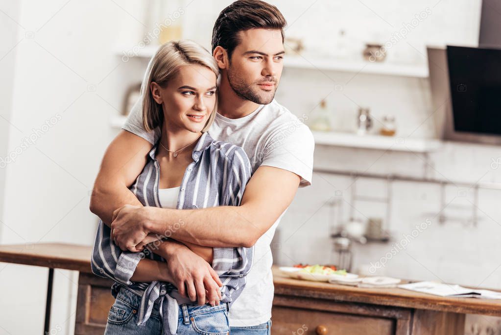 handsome boyfriend and attractive girlfriend hugging in kitchen