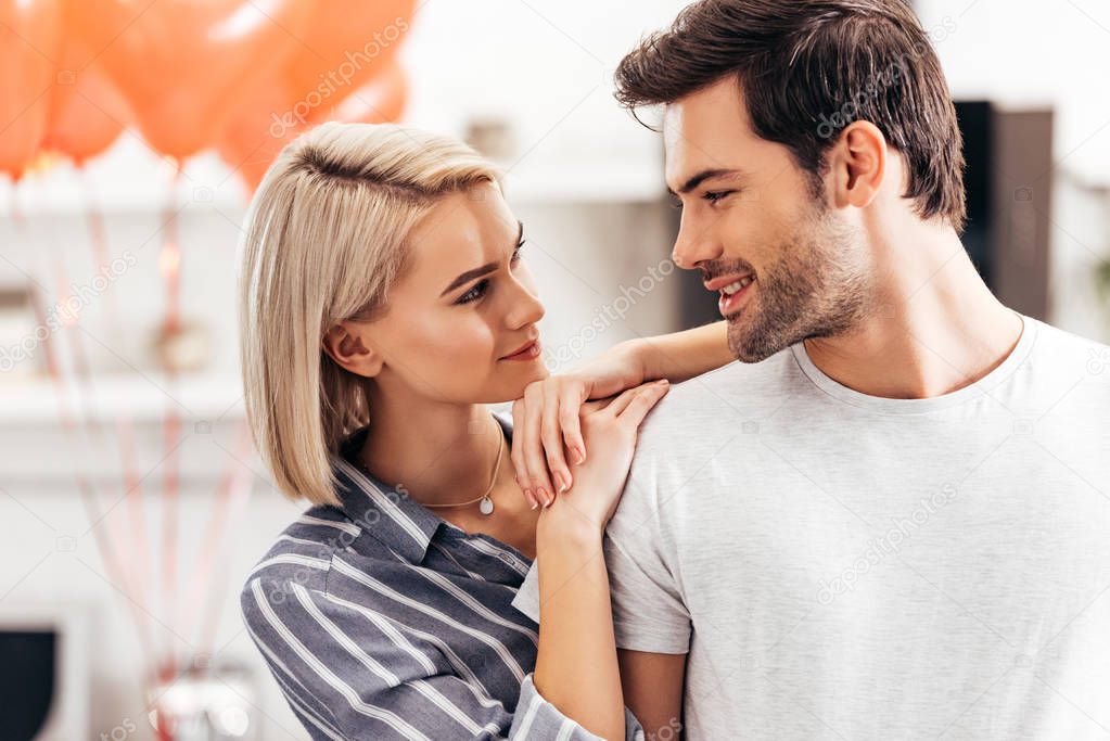 selective focus of handsome boyfriend and attractive girlfriend standing in kitchen on Valentines day