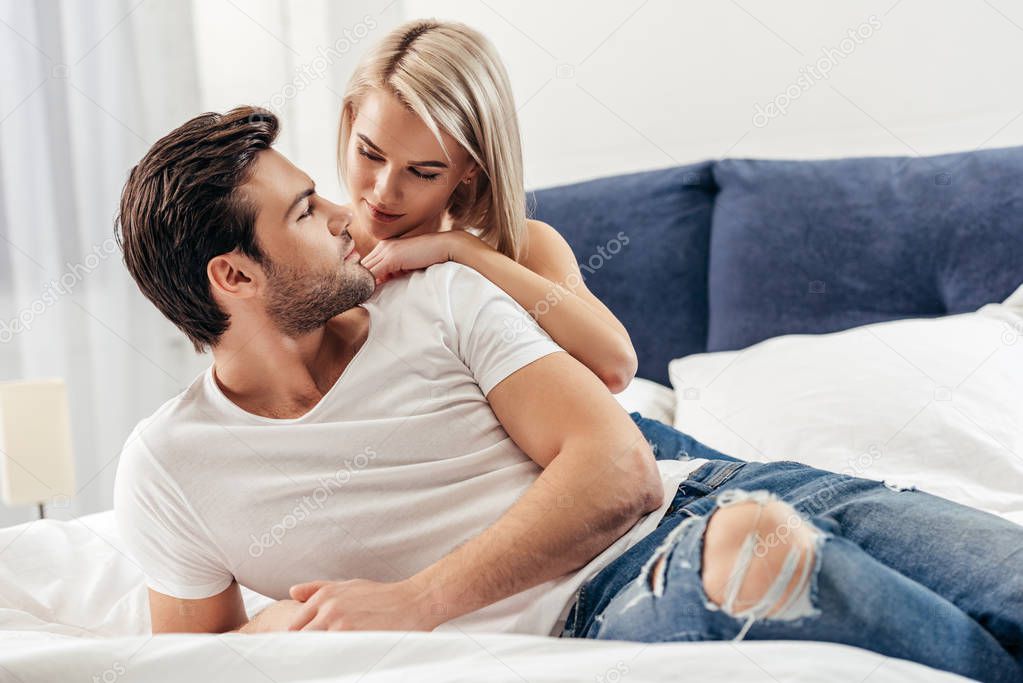 selective focus of attractive girlfriend and handsome boyfriend laying on bed