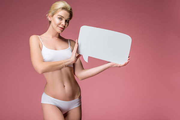 beautiful smiling girl in white underwear posing with empty speech bubble, isolated on pink