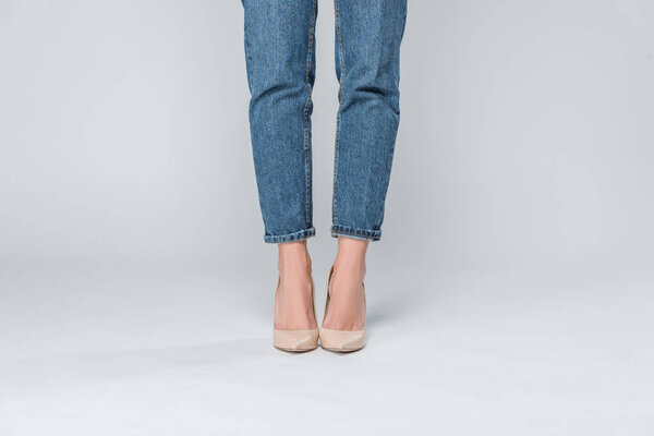 low section view of girl in jeans and high heels isolated on grey 