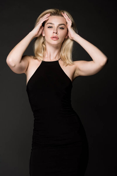 attractive blonde girl in black dress posing isolated on black