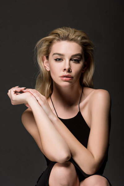 attractive sexy blonde girl in black dress posing isolated on black