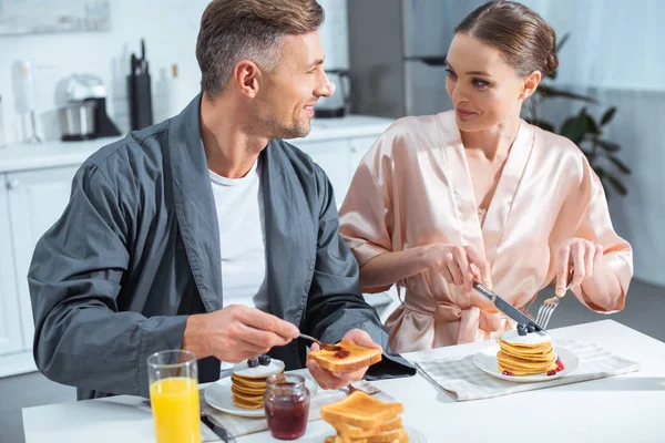 Foco Selectivo Pareja Adulta Batas Durante Desayuno Con Panqueques Jugo — Foto de Stock