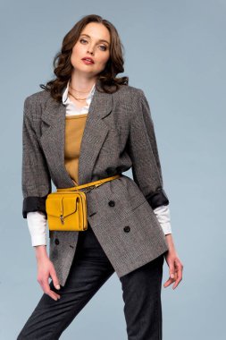 beautiful fashionable woman in formal wear posing and looking at camera isolated on grey