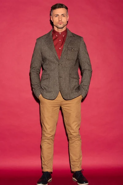 Сфокусированный Стильный Мужчина Формальной Одежде Смотрит Камеру Красном Фоне — стоковое фото